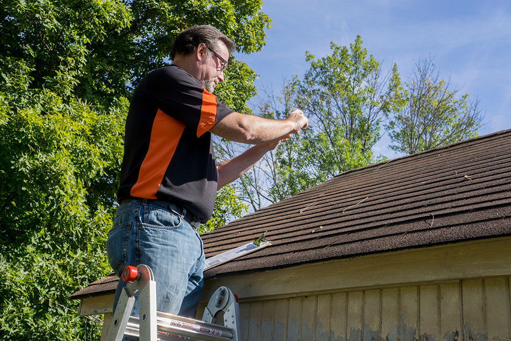 photo of a home inspector taking a photo of a garage roof in Edmonton, identifying issues with the roof condition before the same of a home